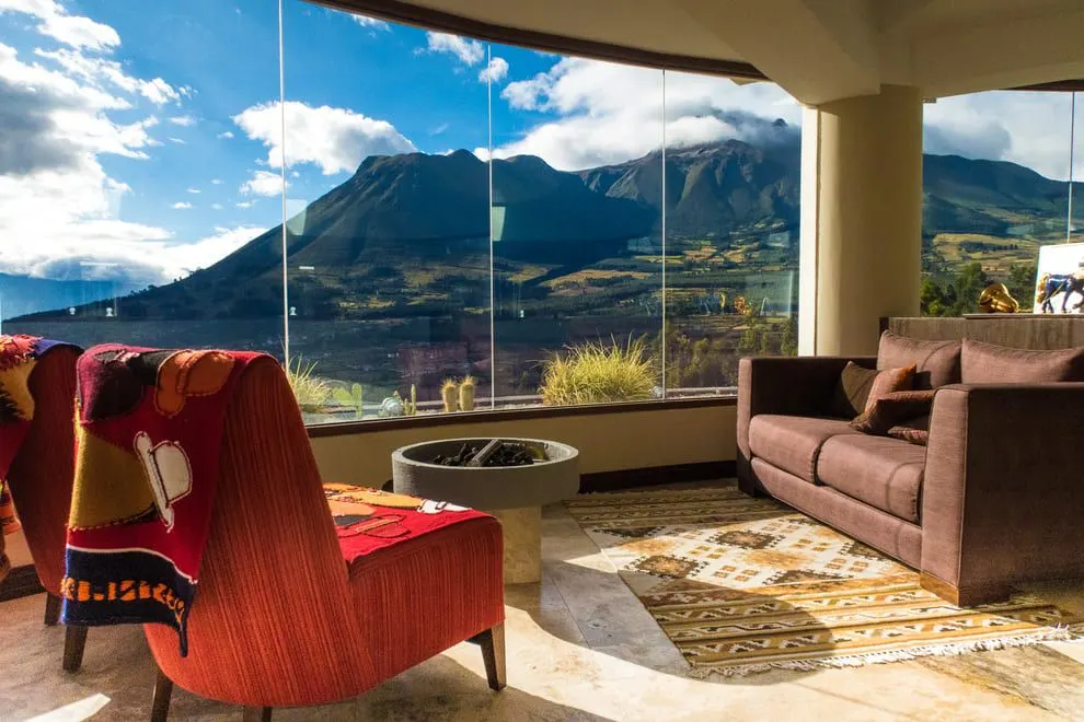 Sala de estar con ventanal hacia el Imbabura, sillones y alfombras tejidas